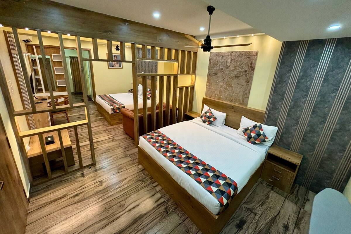 A hotel room with a large bed, a desk, and a chair. There is a ceiling fan and a wall-mounted TV.