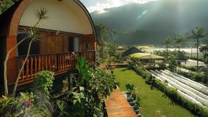 Una villa moderna con un balcone curvo, un giardino rigoglioso e vista sulle montagne lontane.