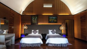 Camera d'albergo con due letti, una scrivania e uno specchio. Ci sono due comodini con lampade, e la stanza ha pareti in legno e un soffitto curvo.