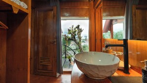 Ambiente interno in legno con un lavabo in grande ciotola, vista su un albero all'esterno e una scala che conduce a una zona esterna.