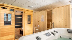 Sauna, jonka sisäseinät ovat puuta, ja jossa on poreallas sekä ohjauspaneeli.