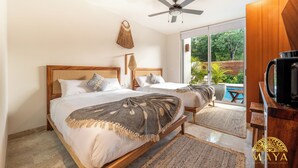 Camera da letto con due letti, un ventilatore a soffitto, una TV e vista su una piscina.