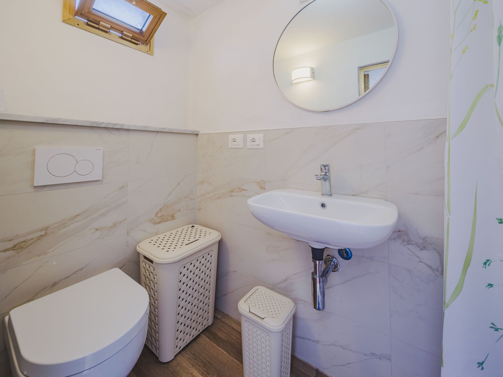 A bathroom with a toilet, a sink, a mirror, and a window.