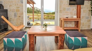 A cozy living room with a stone wall, a wooden table, two cushioned chairs, a TV, and a fireplace. - Vacation home Lea by Interhome (Karlobag)