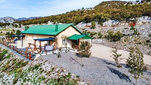 A building with a green roof and beige walls, surrounded by rocky terrain and sparse vegetation. - Vacation home Lea by Interhome (Karlobag)