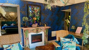 A room with a fireplace, a bed, a chair, and a table. - Le Jardin Perché: Suite for Two (MOULEYDIER)