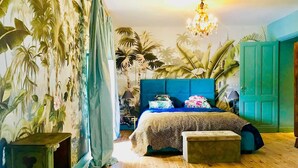 A bedroom with a large bed, a nightstand, a dresser, and a green door. - Le Jardin Perché: Suite for Two (MOULEYDIER)
