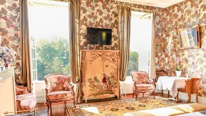 A room with a bed, two armchairs, a sofa, a television, and a table with a chair. - Bed and Breakfast for Two (MOULEYDIER)