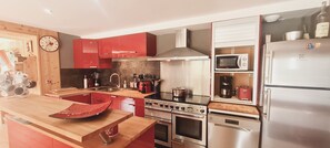 Une cuisine moderne avec des armoires rouges, des appareils en acier inoxydable et un plan de travail en bois.