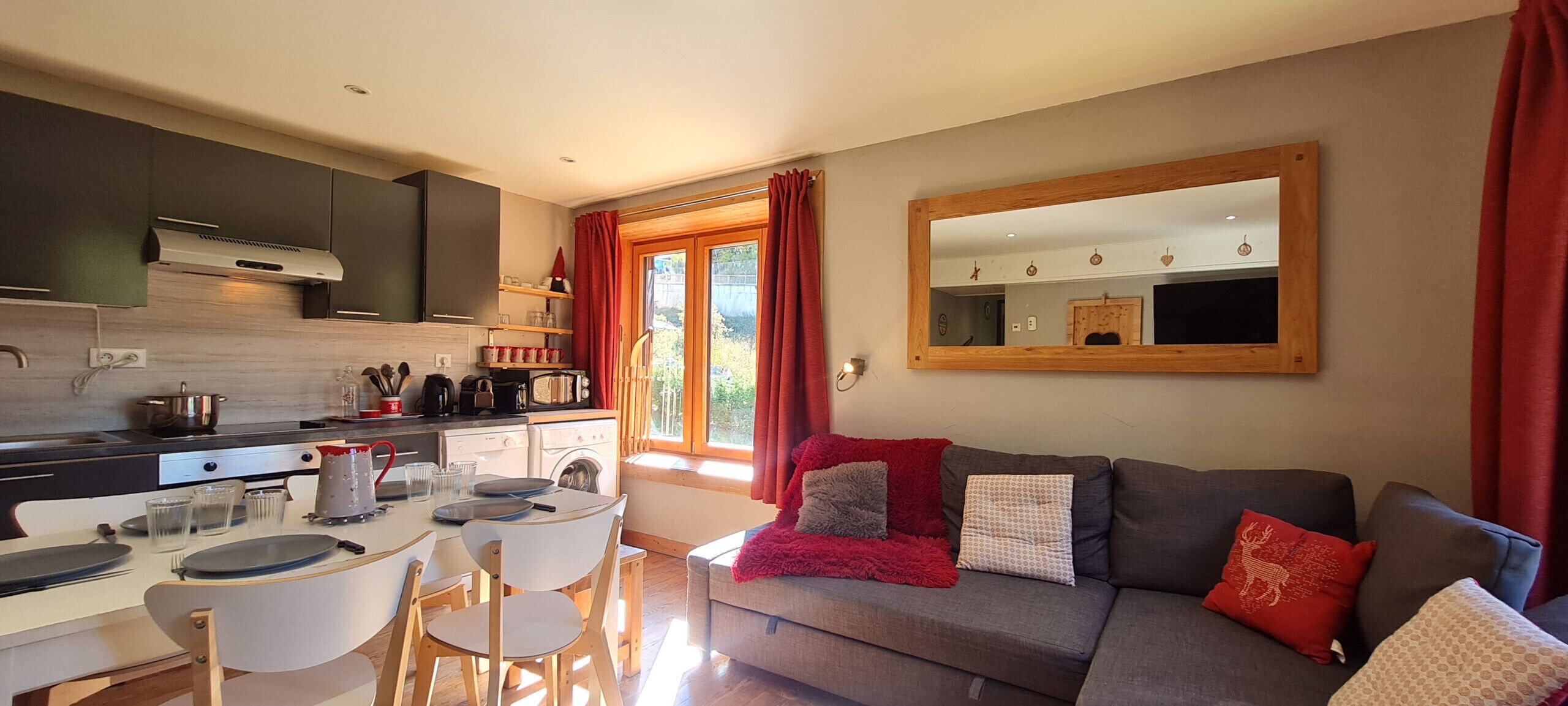 Une cuisine moderne avec un coin repas, un canapé avec des coussins et un grand miroir au mur.