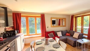A modern kitchen with a dining area, large windows, and a cozy seating arrangement.