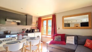 A modern kitchen with a dining area, a sofa with cushions, and a large mirror.