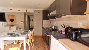 A modern kitchen with a dining table, chairs, and a TV mounted above the table.