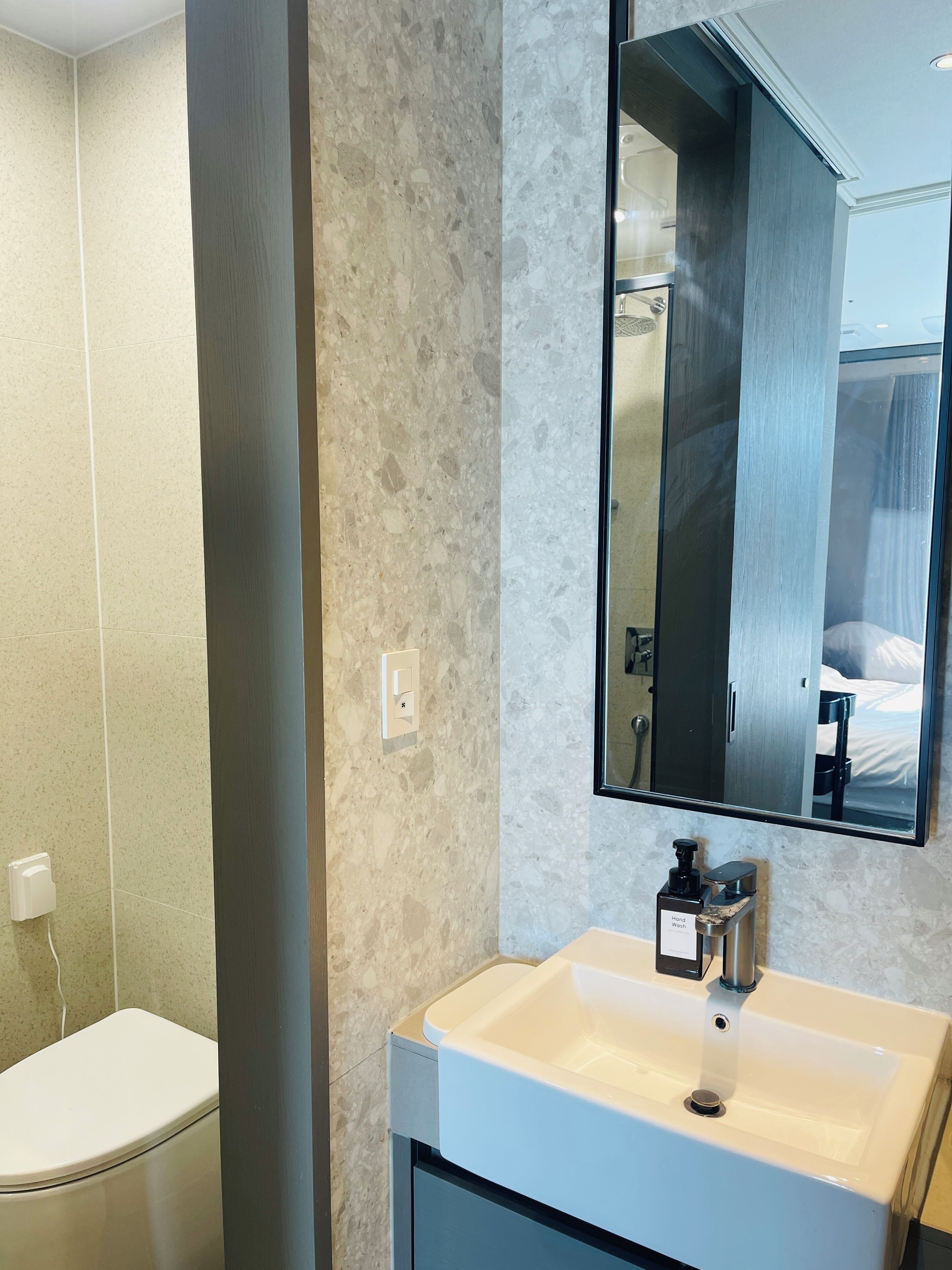 A modern bathroom with a white sink, a mirror, and a toilet.