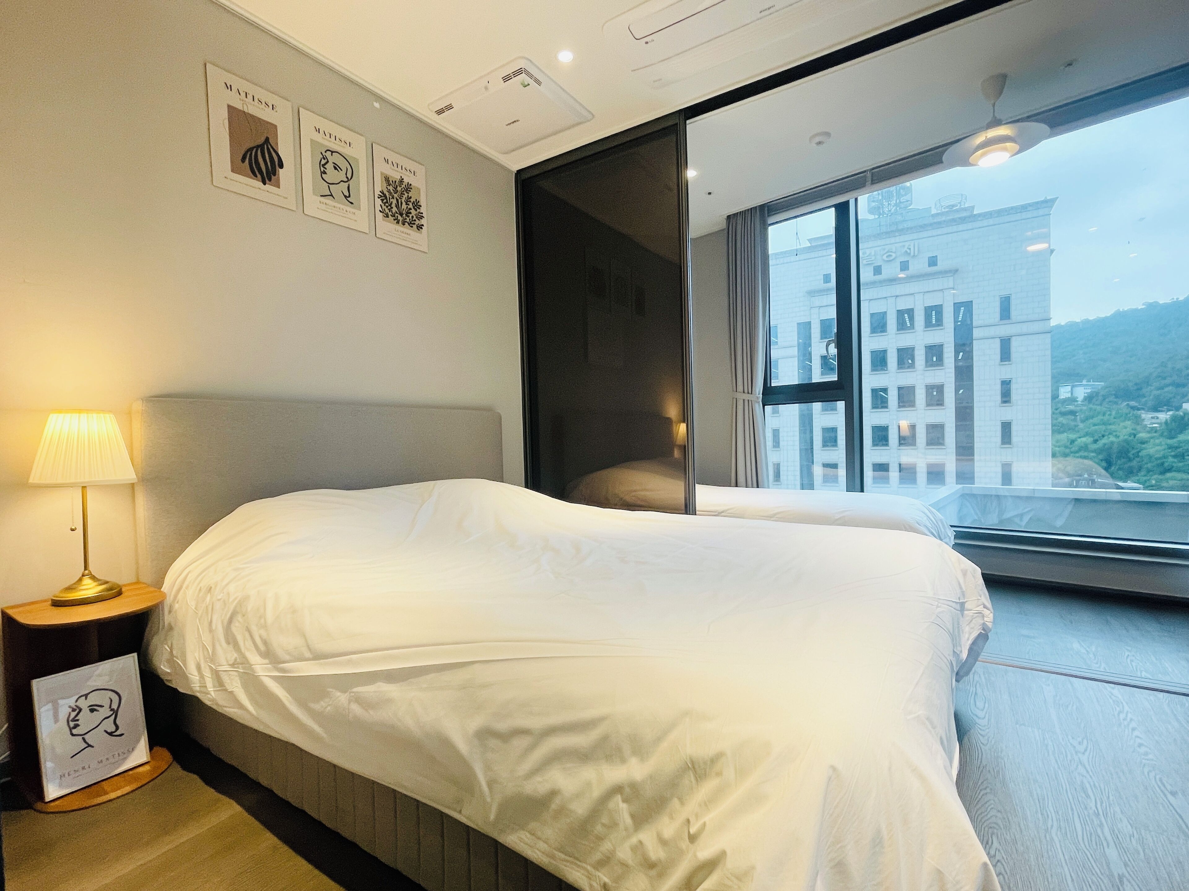 Ein Hotelzimmer mit einem großen Bett, einer Nachttischlampe und gerahmten Kunstwerken an der Wand.