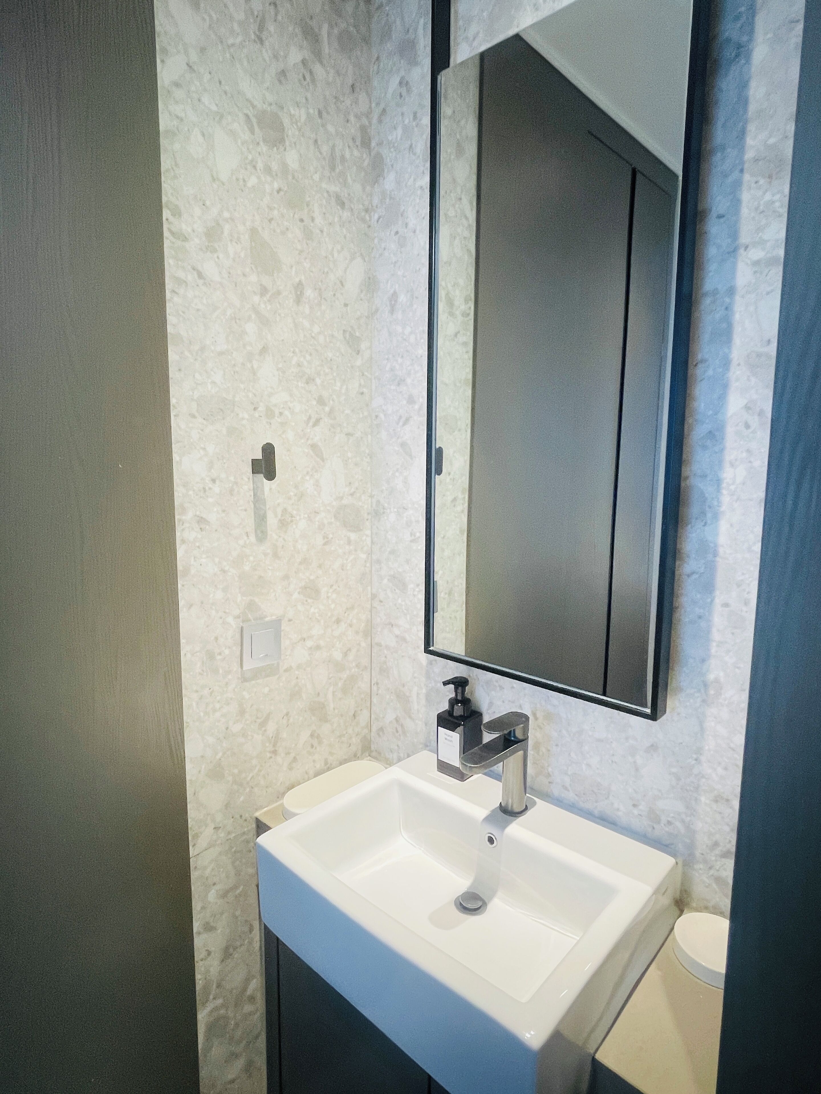 A bathroom with a white sink, a mirror, and a toilet.