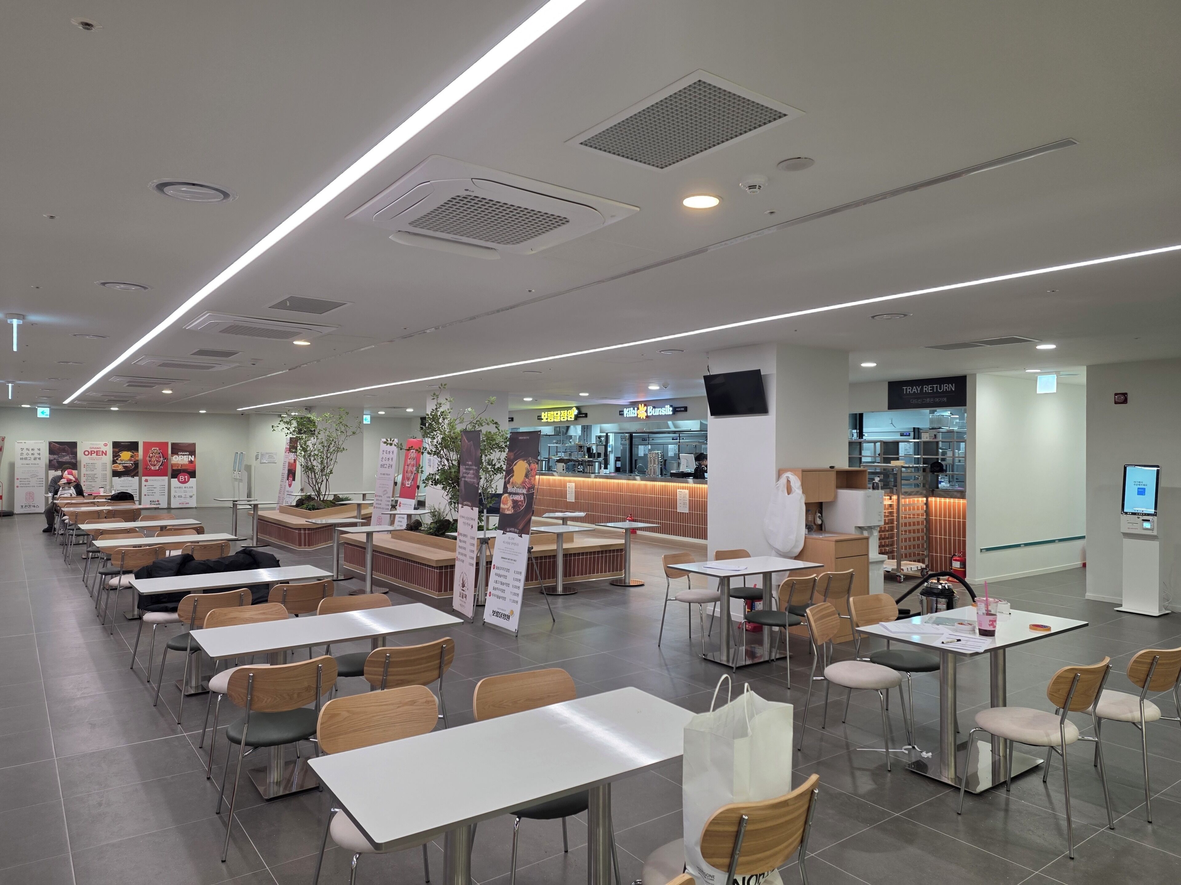 A spacious indoor dining area with multiple tables and chairs, a counter with a menu, and a trash bin.
