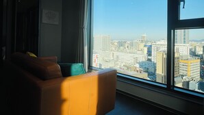 A room with a large window offering a city view, a brown leather sofa, and a green cushion. - villiv Inn The City Namsan (Seoul)