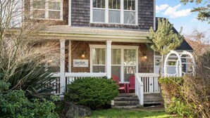 A two-story house with a porch, a sign reading "Storybook Bed & Breakfast," and a small garden area.