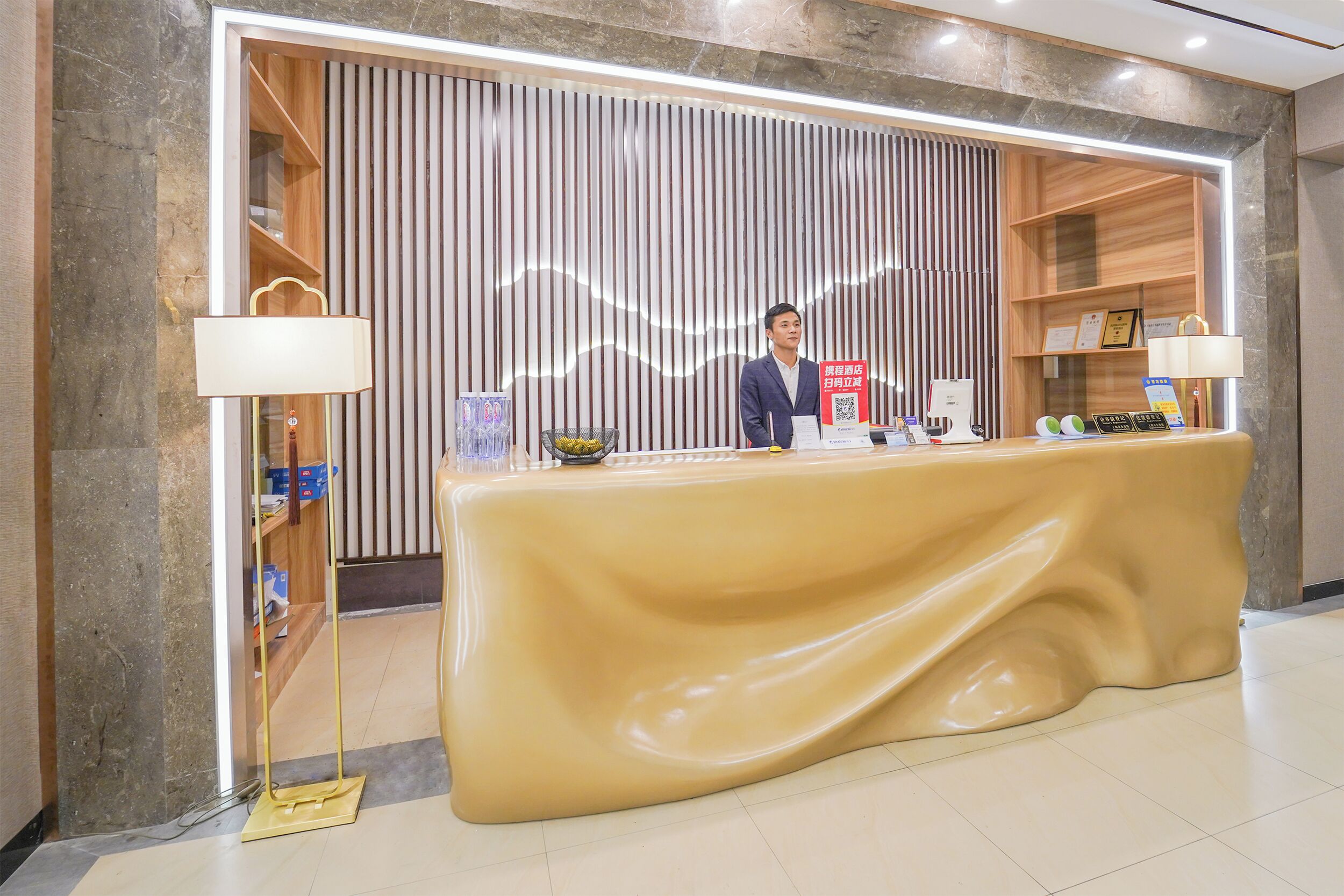 Un mostrador de recepción con un fondo de pared de mármol, diseño de paneles de madera y mantel amarillo.