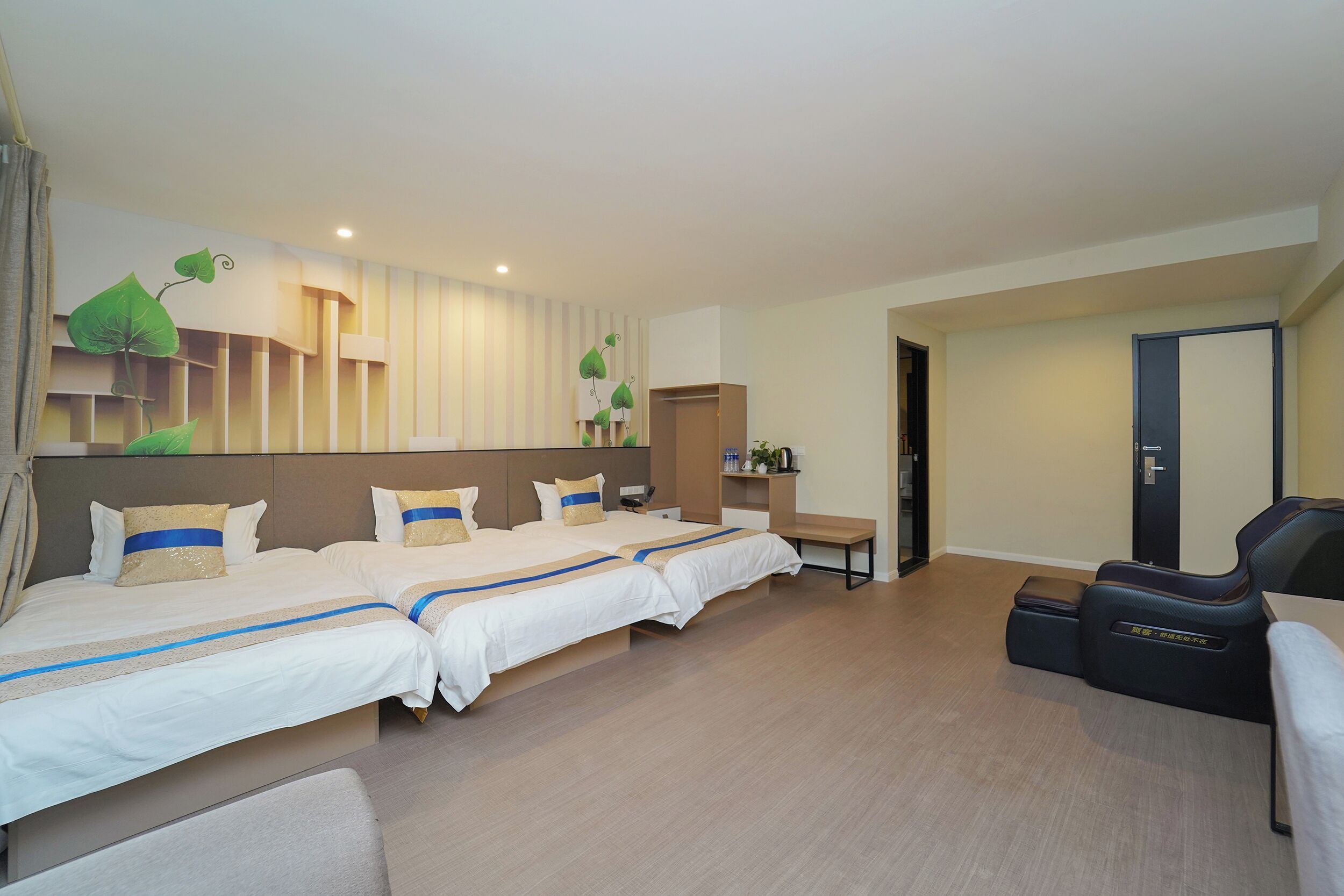 A hotel room with two beds, a massage chair, a desk, and a wardrobe.