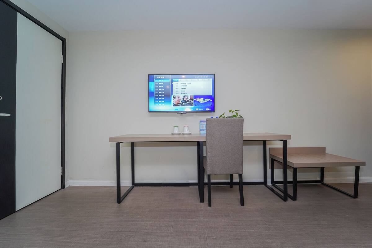 A modern room with a desk, chair, and a flat-screen TV mounted on the wall.