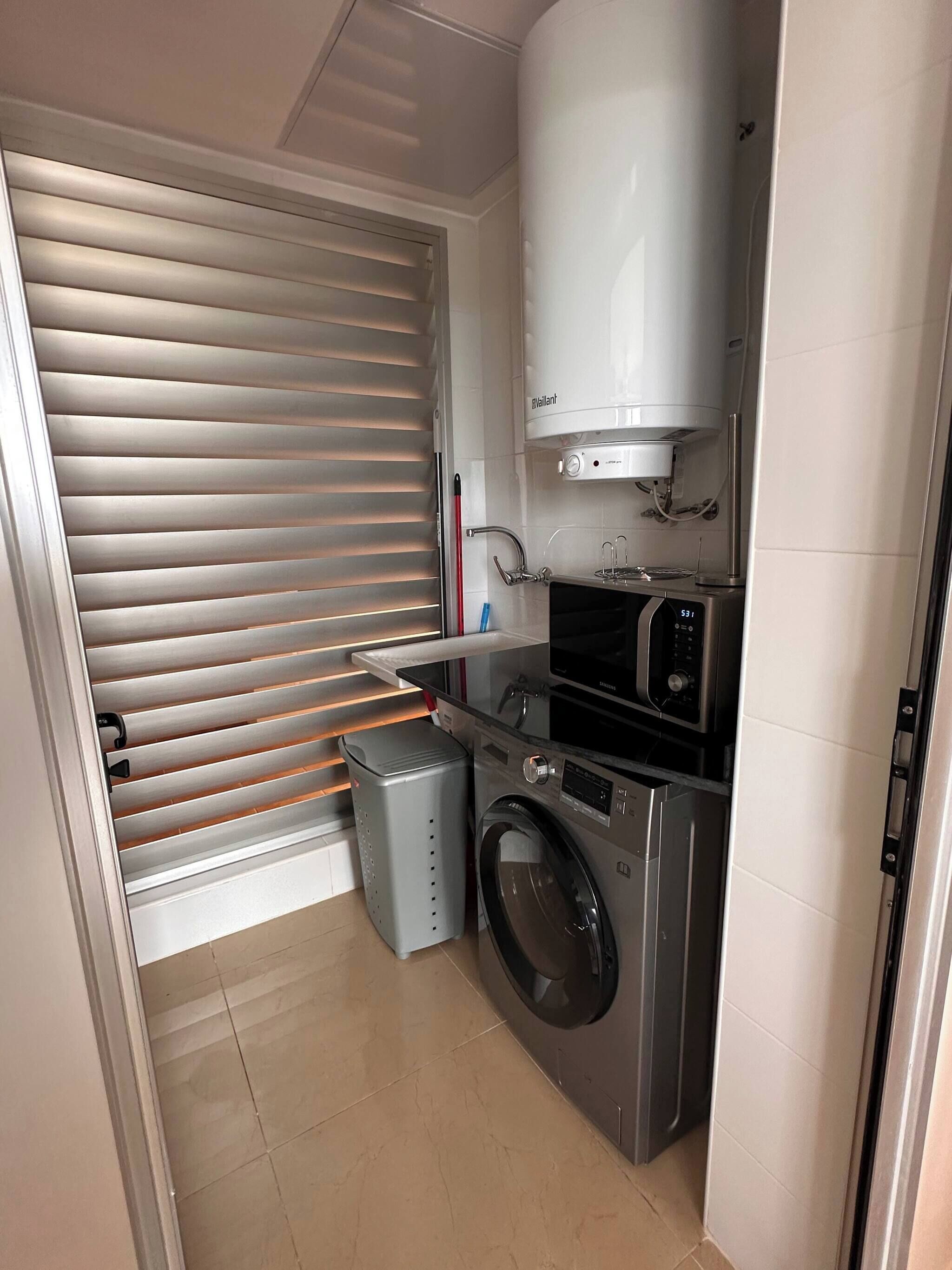 A compact laundry room with a washing machine, dryer, and a water heater.