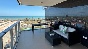 A balcony with a sofa and a small table, overlooking a beach and a golf course. - World Magic Vacaciones 5 (Cabanes)