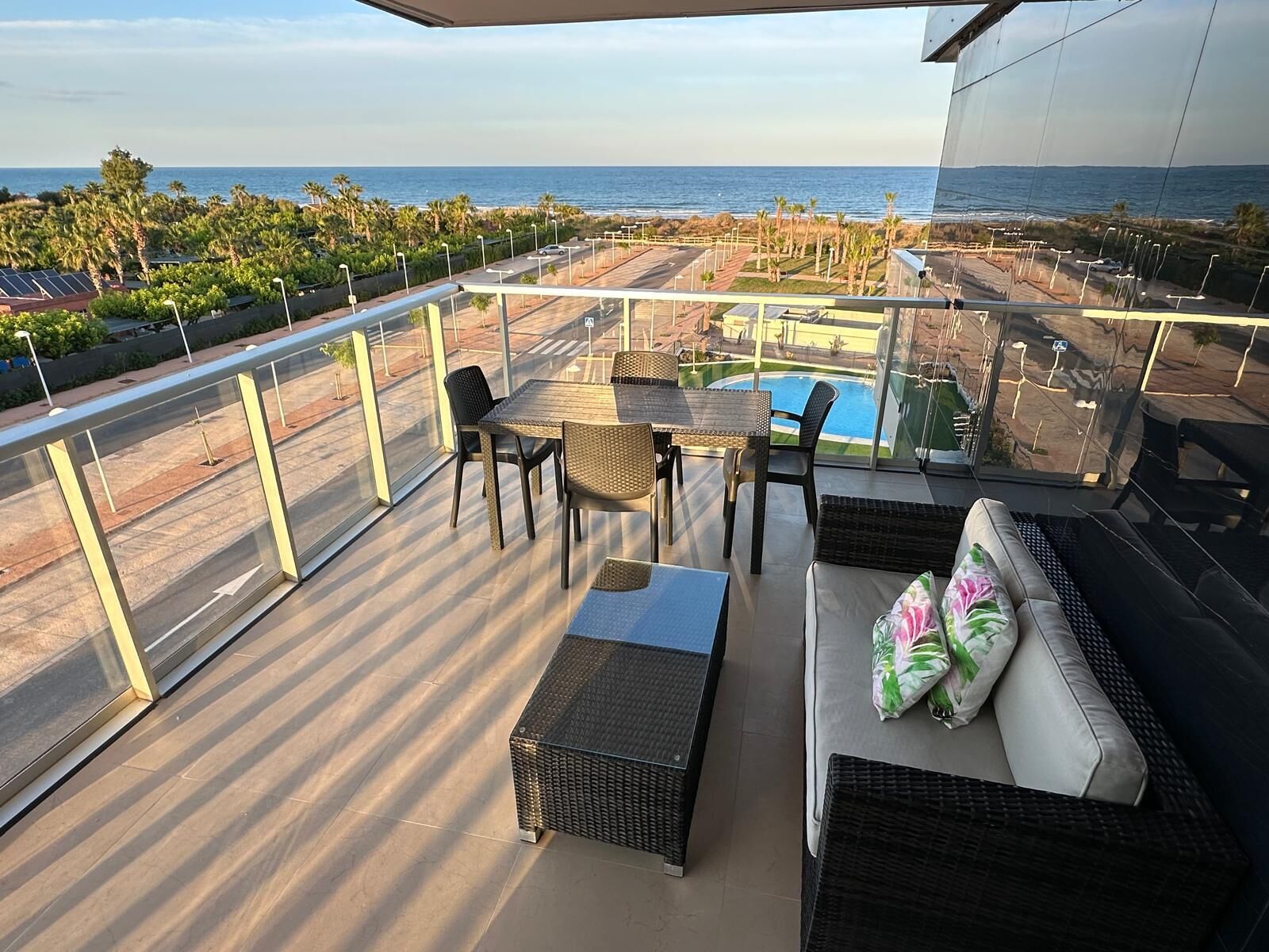 Uma varanda com vista para o oceano, uma piscina e um espaço de refeições com cadeiras e mesas.