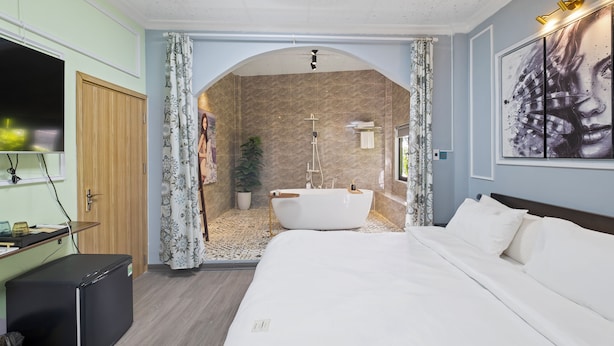 Un dormitorio moderno con una cama grande, una bañera integrada y una ducha.