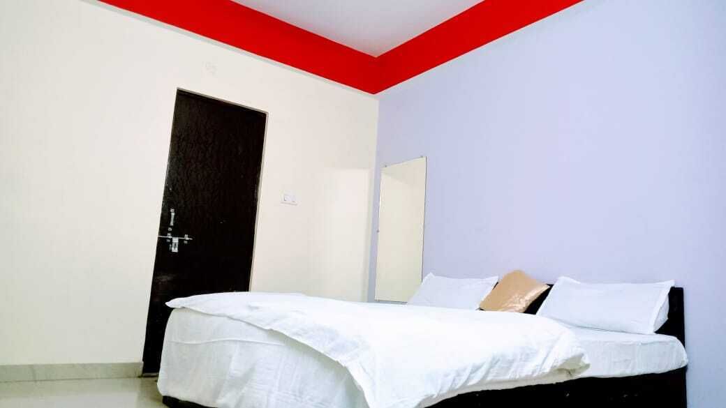 Un dormitorio con cama, una puerta y un espejo en la pared.