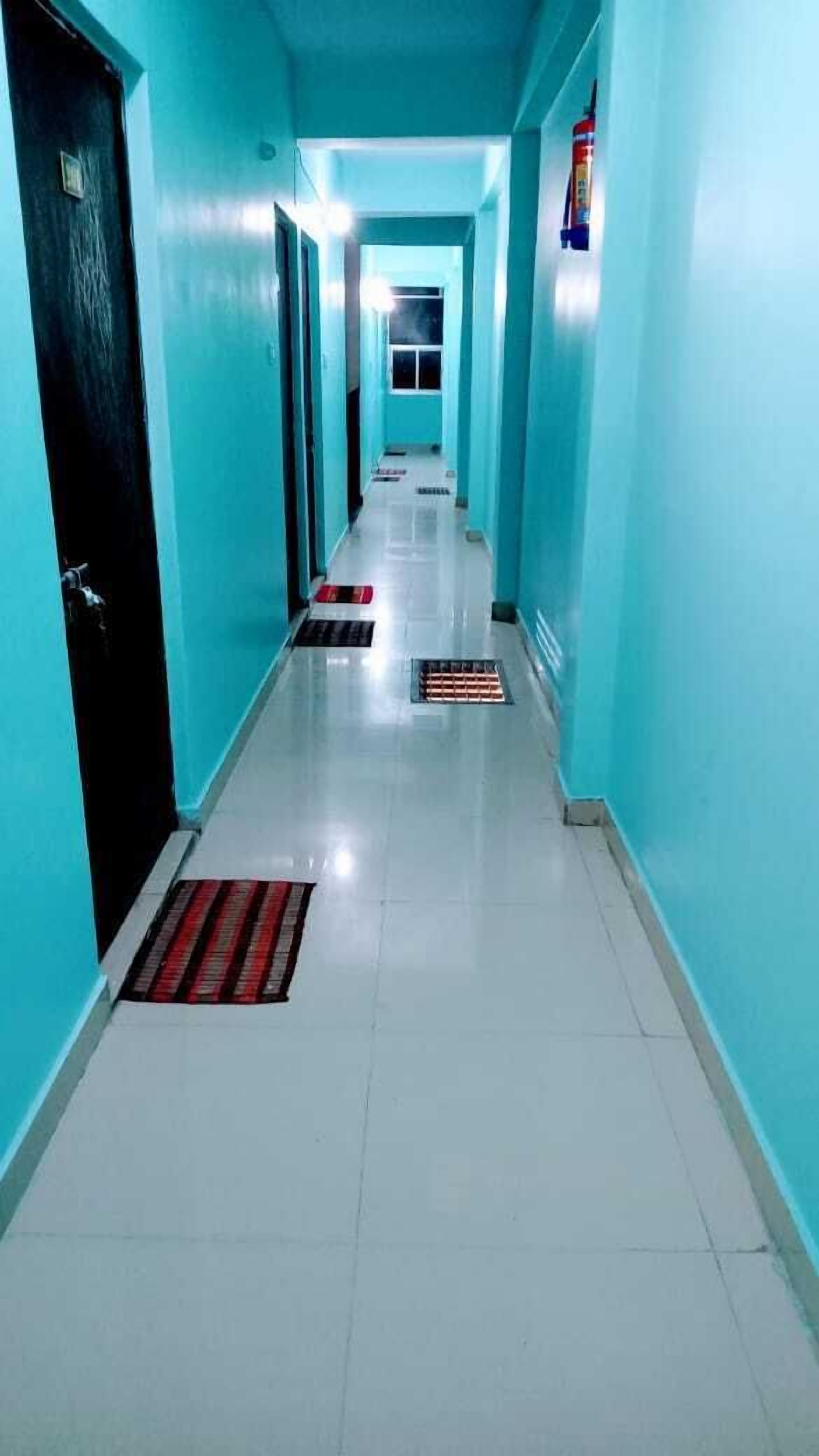A hallway with teal walls and white floors, leading to a door at the end.