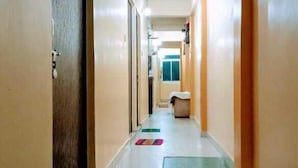 A hotel hallway with doors on both sides, a central walkway, and a small seating area at the end. - The Shivay Guest House (Varanasi)