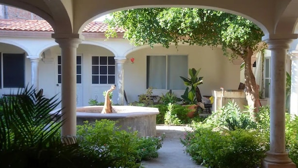 A covered courtyard with a central fountain, surrounded by lush greenery and potted plants. - Hotel Boutique Los Arcos (Los Mochis)