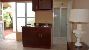 A kitchen with a wooden cabinet, a sink, and a white lamp. - Hotel Boutique Los Arcos (Los Mochis)