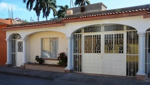 A two-story house with a white facade, large arched windows, and a gated entrance. - Hotel Boutique Los Arcos (Los Mochis)