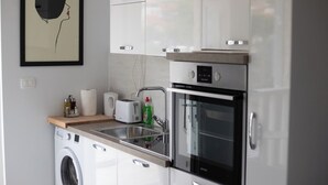 A modern kitchen with a washing machine, a toaster, a sink, and an oven. - Harbour View House Studio Apartment  (Zaton)