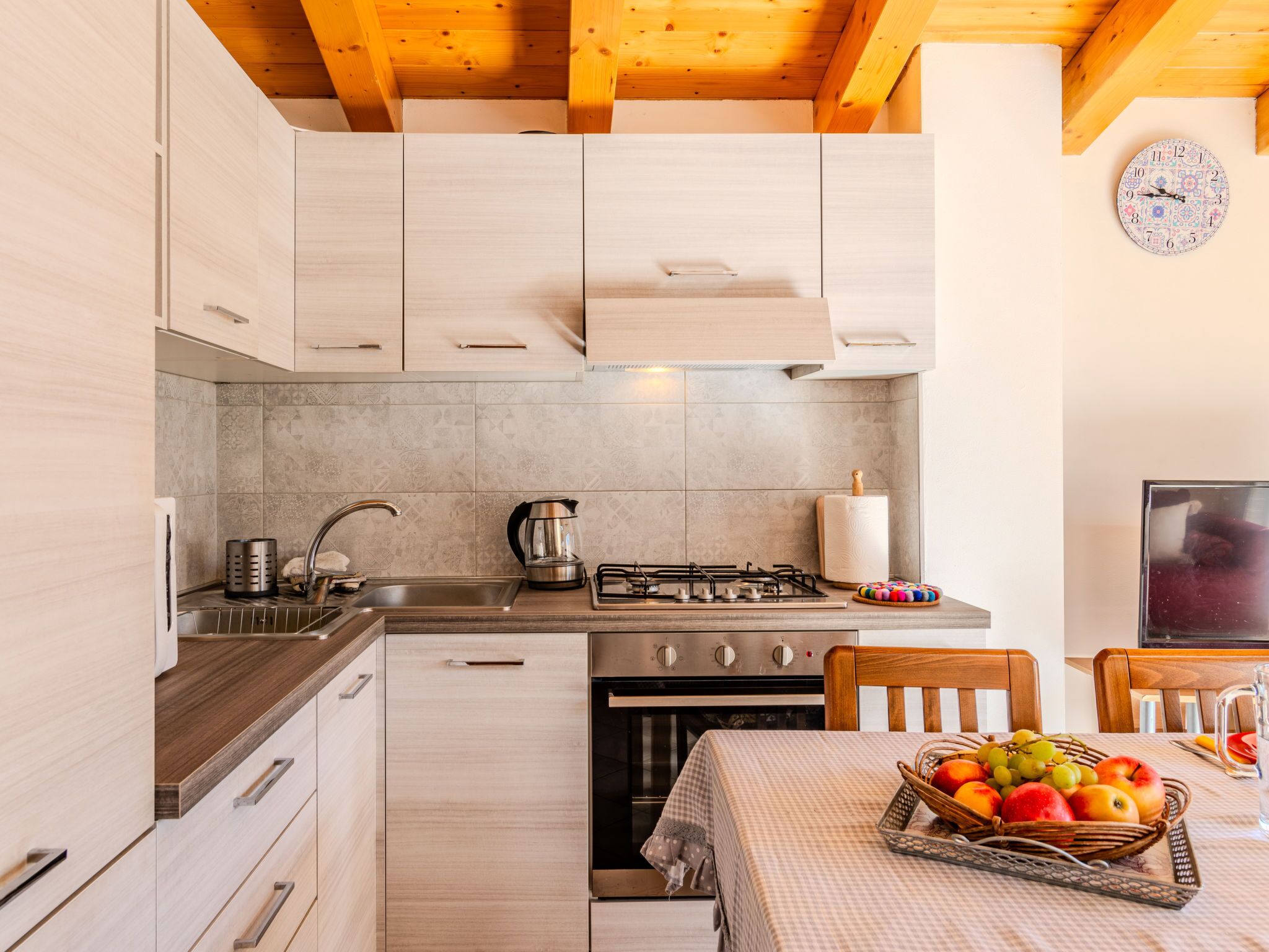 A modern kitchen with wooden cabinets, a gas stove, and a dining area with a table set for two.