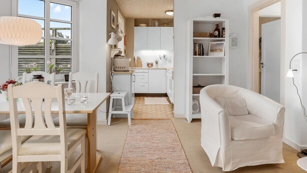 Una sala de estar moderna y bien iluminada, con comedor, cocina y una zona de estar acogedora.