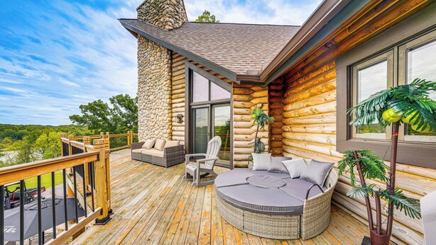 Een vakantiehuis in blokhutstijl met terras, buitenmeubels en een groot raam.