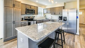 Una cocina moderna con encimeras de granito, electrodomésticos de acero inoxidable y armarios de madera.