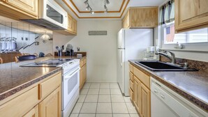 A kitchen with wooden cabinets, a microwave, stove, refrigerator, and a sink.
