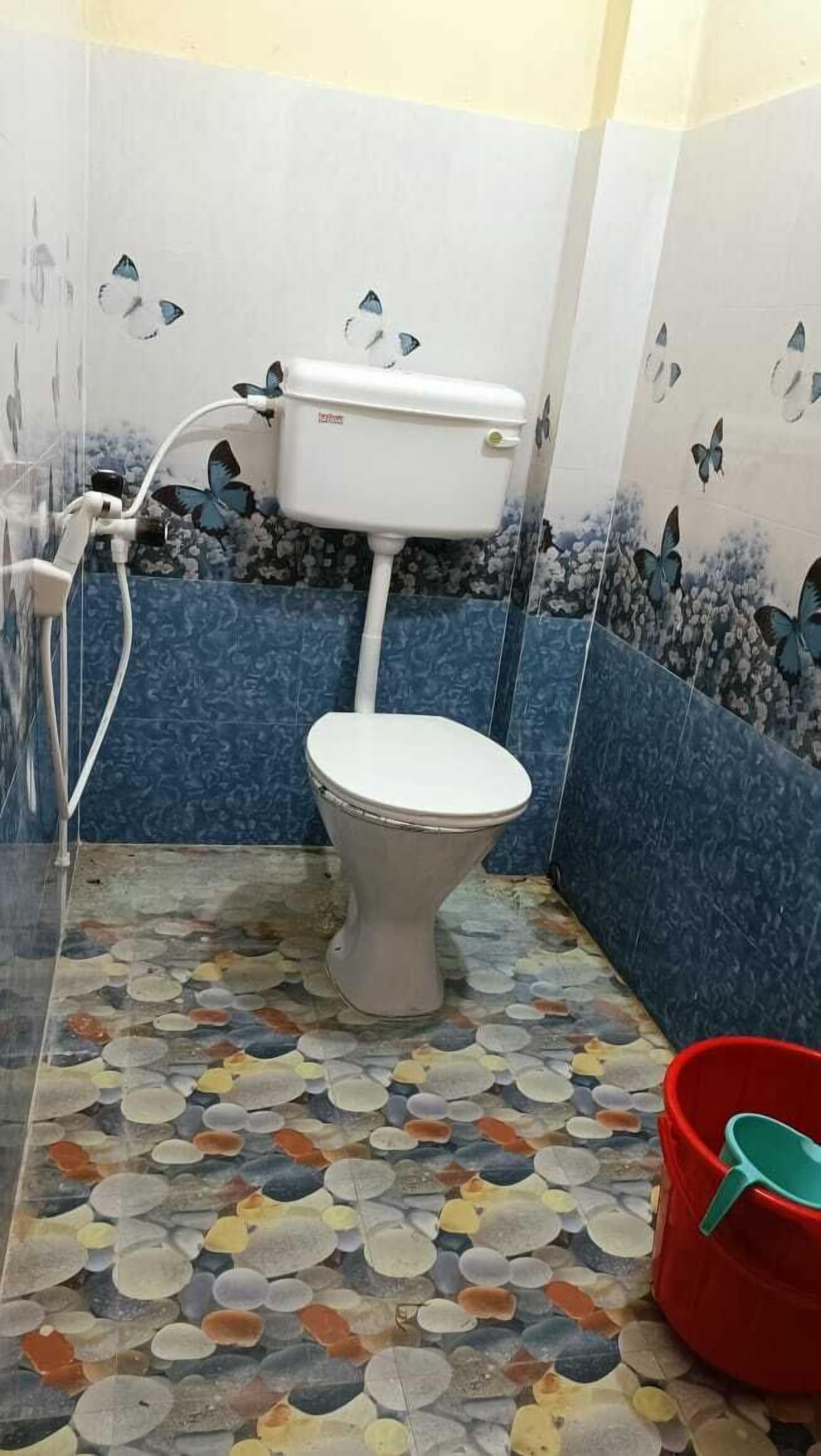 A bathroom with a toilet, a shower, and a floor with colorful pebbles.