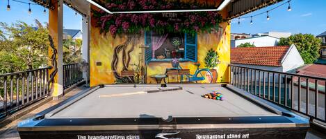A pool table with a mural, surrounded by a railing, and a sign reading 'VICTORY.'