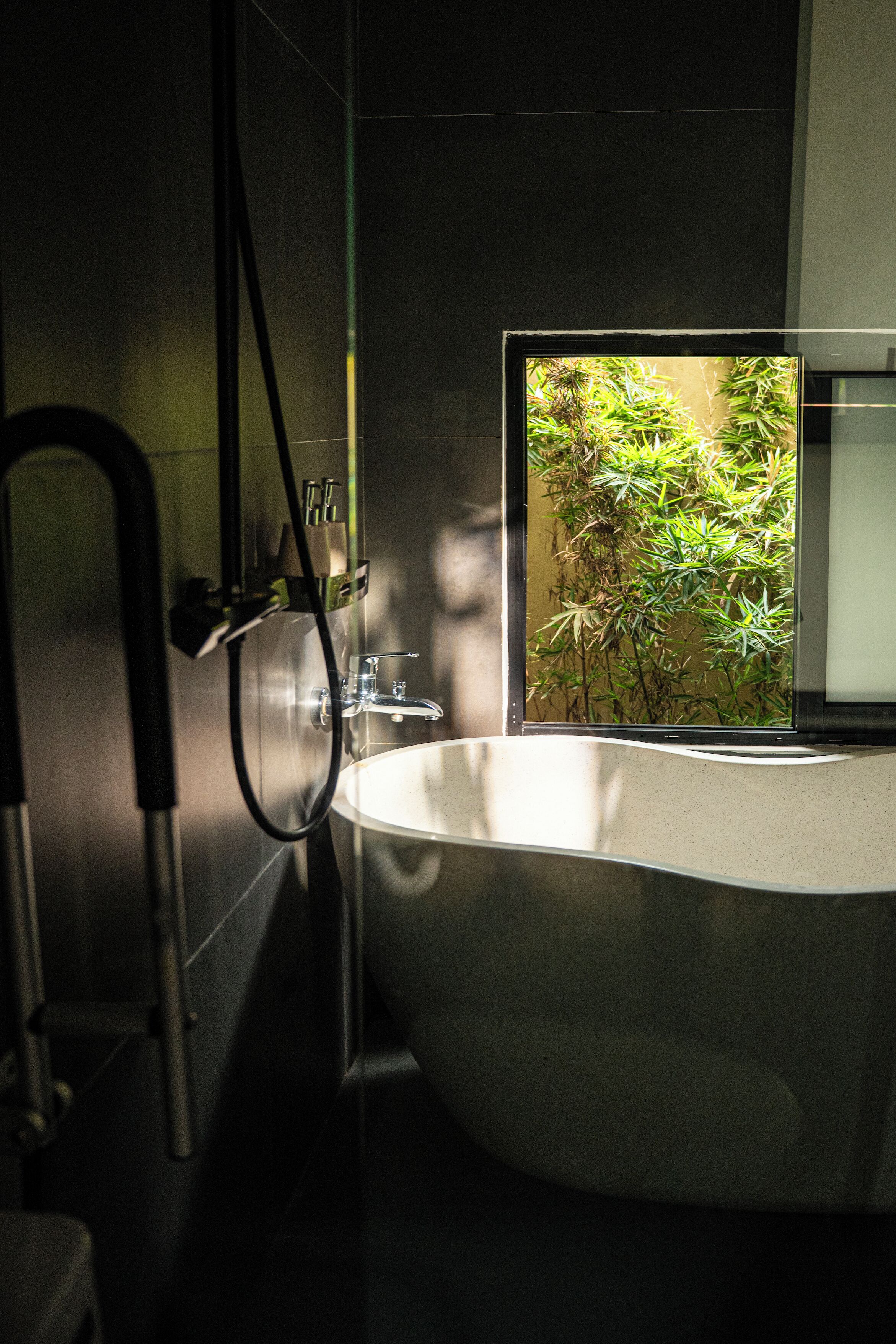 Un baño moderno con una bañera independiente, un cabezal de ducha visible y un lavamanos montado en la pared.