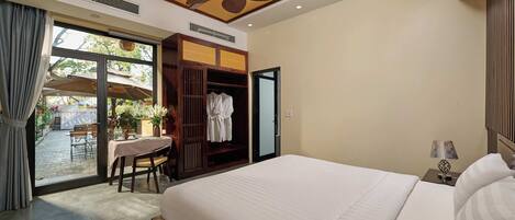 A hotel room with a large bed, a ceiling fan, a table with chairs, and a view of the outside.