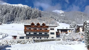 Un hôtel à plusieurs étages, doté de balcons en bois, qui se dresse sur fond de montagnes enneigées.