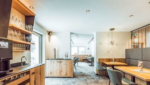Une cuisine moderne avec des meubles en bois, un coin bar avec des verres et un espace détente avec des tables et des chaises.