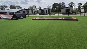A grassy area with a trampoline and a small building. - Noordzee Deluxe 32 by Interhome (Scherpenisse)