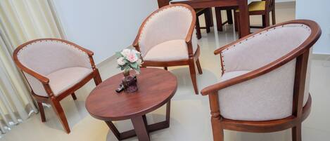 A dining area with wooden chairs and a round table, featuring a vase with flowers.
